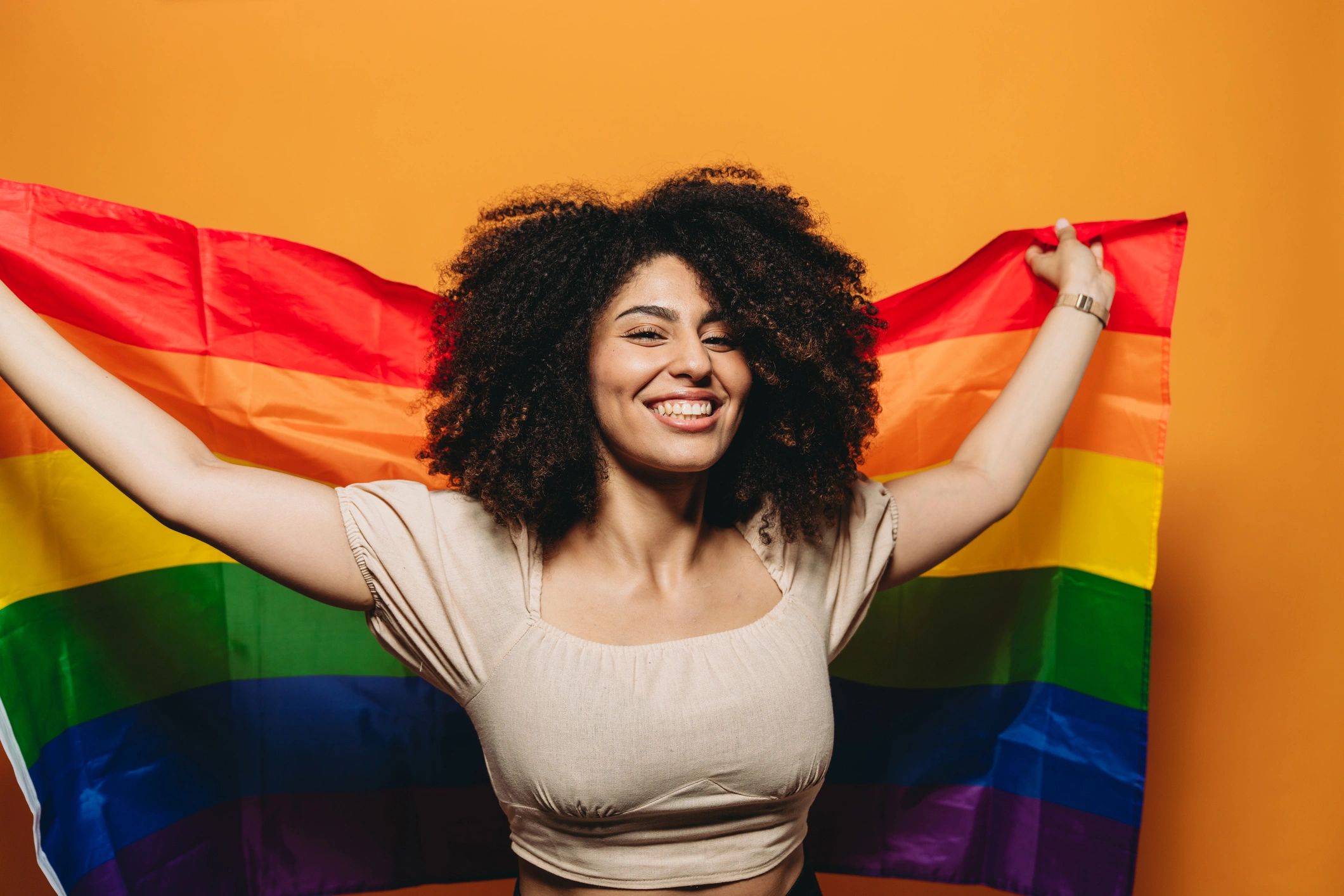 Person holding a rainbow flag, representing pride and belonging