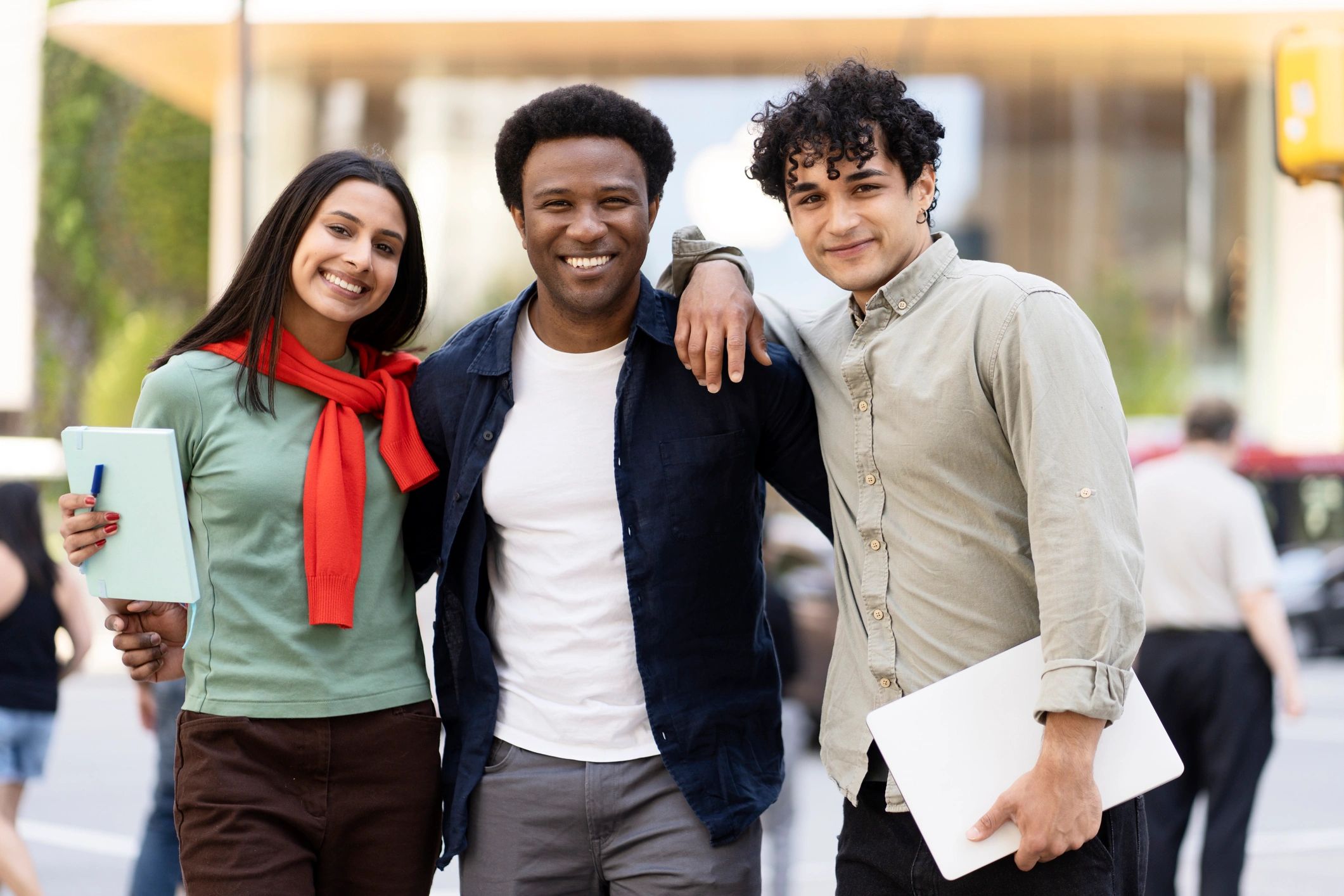 Three students smiling together outdoors, representing youth programs
